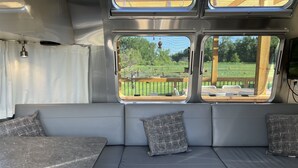 Interior moderno de autocaravana con sofá gris, dos almohadas y una encimera de mármol.
