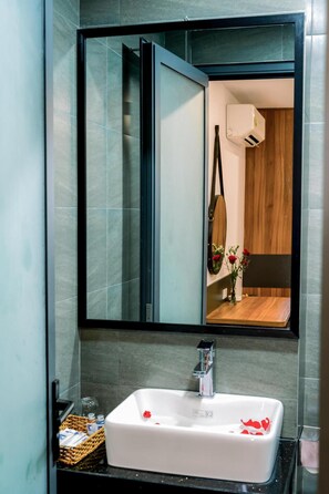 A bathroom with a white sink, a mirror, and a wooden vanity. - Kadupul Hotel (Quy Nhon Nam)