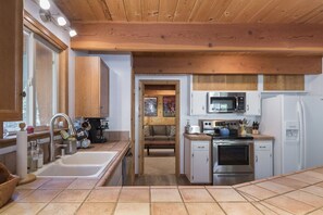 Compact kitchen with a stainless steel sink, microwave, and refrigerator, perfect for preparing meals.