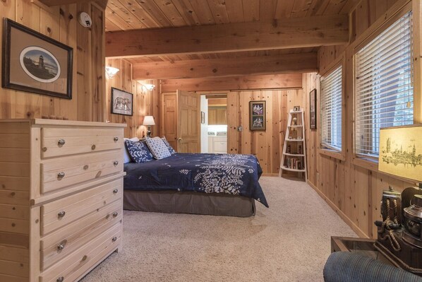 Ein Schlafzimmer einer Holzhütte mit Bett, Kommode und einer Leiterregal.