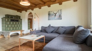 Uma sala de estar moderna com um sofá seccional, uma mesa de centro, uma lareira e um quadro com veados.