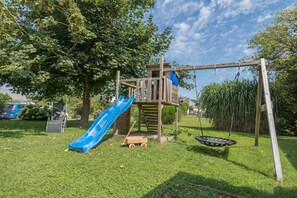 A playground with a slide, swing set, and climbing structure. - Apartment OG1 in "Gästehaus Heinemann" right on Lake Constance with lake view (Langenargen)