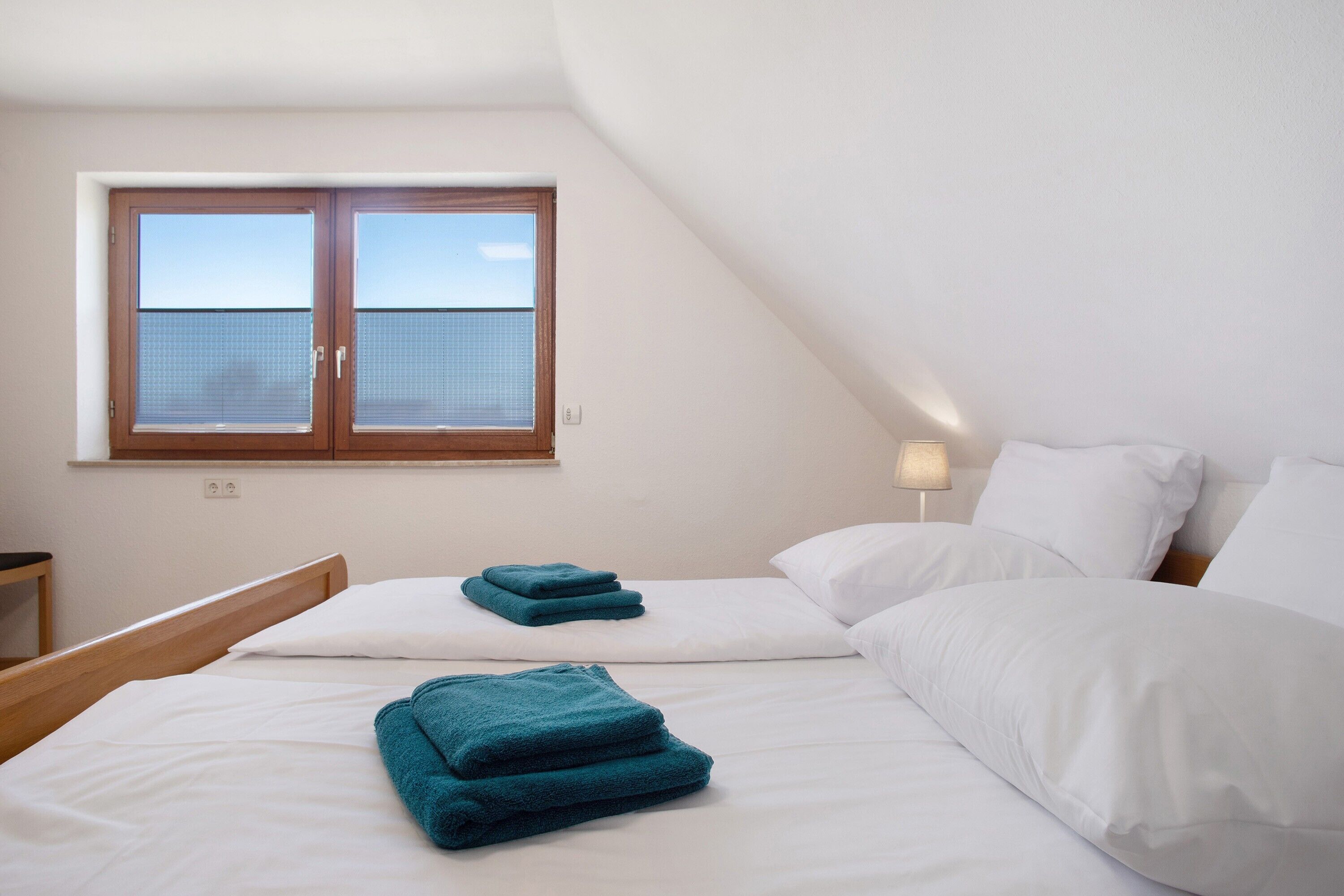 Une chambre avec deux lits, une fenêtre et une lampe de chevet.