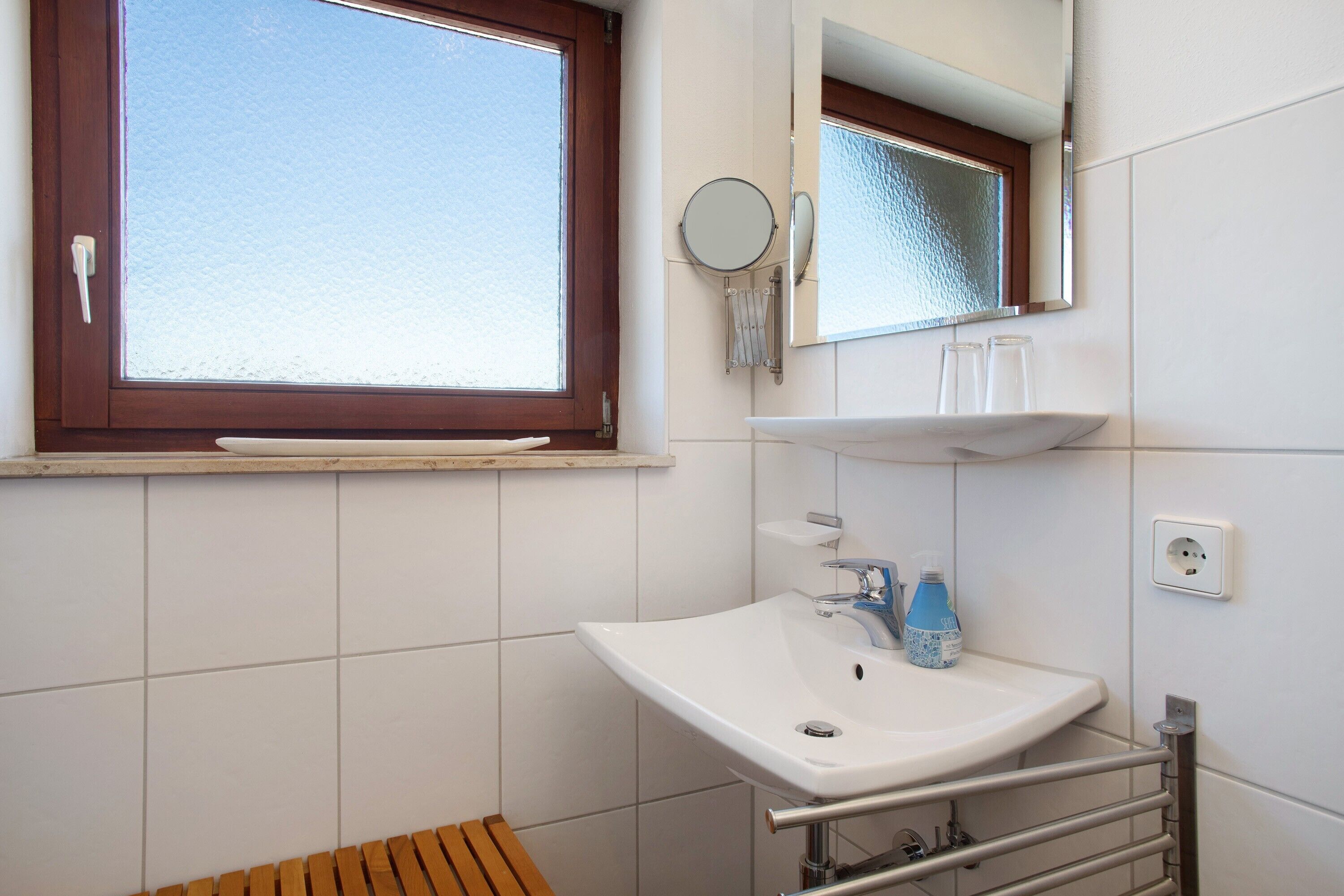 Ein Badezimmer mit Fenster, Waschbecken, Spiegel und Handtuchhalter.