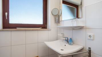 Ein Badezimmer mit Fenster, Waschbecken, Spiegel und Handtuchhalter.