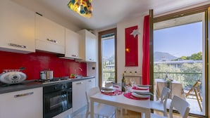 A modern kitchen with white cabinets, a red accent wall, and a dining area with a table set for four.