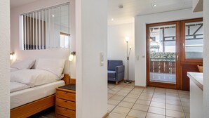 A bedroom with a bed, bedside table, and a window with blinds.