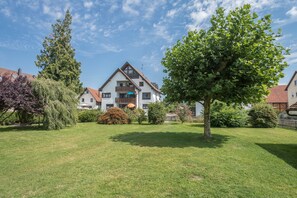 A residential building with a sloped roof, a balcony, and a well-maintained lawn.