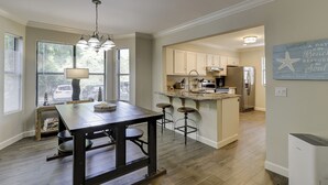 A kitchen with a central island, bar stools, and a hanging light fixture.