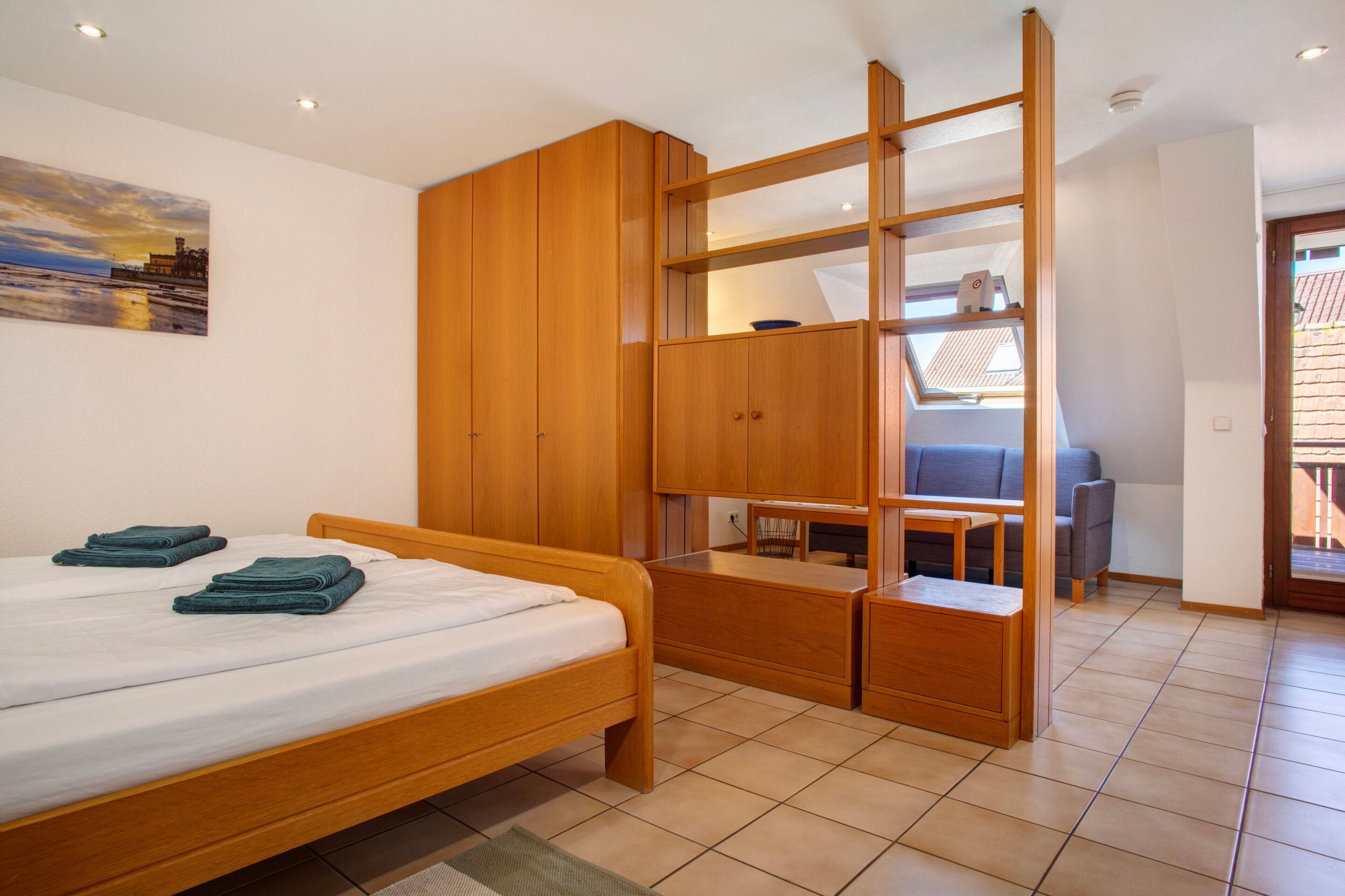 Ein Schlafzimmer mit Bett, Holzschrank und Schreibtisch mit Stuhl.