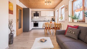 Une cuisine moderne avec des meubles blancs, une table à manger avec des chaises et un canapé agrémenté de coussins décoratifs.