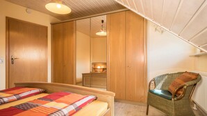 Une chambre à coucher avec un lit, une chaise et une armoire.