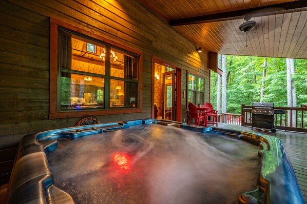 Un bain à remous sur une terrasse en bois, avec vue sur les arbres.