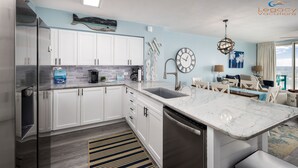 Una cocina moderna con armarios blancos, encimera de mármol y lavavajillas de acero inoxidable.