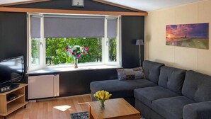 Uma sala de estar moderna com uma janela grande, uma TV de tela plana, um sofá e um quadro na parede.
