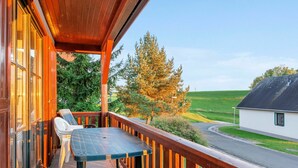 A wooden balcony with a table and chairs, overlooking a road and green fields. - Wonderful private villa for 6 people with WIFI, pool, TV, terrace and pets allowed (Dvur Králové Nad Labem)