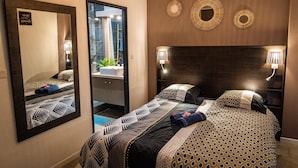 Ein Hotelzimmer mit zwei Betten, einem großen Spiegel, Wandklimaanlage und dekorativen Wandleuchten.