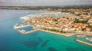 An aerial view of a coastal town with a marina, buildings with red roofs, and clear blue waters. - Apartment Petra by Interhome (Biograd na Moru)