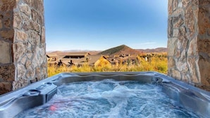 A hot tub with a view of a town and mountains.