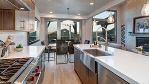A modern kitchen with a large island, stainless steel appliances, and a view of a mountain.