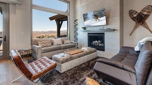 A modern living room with a large window, a fireplace, and a television.