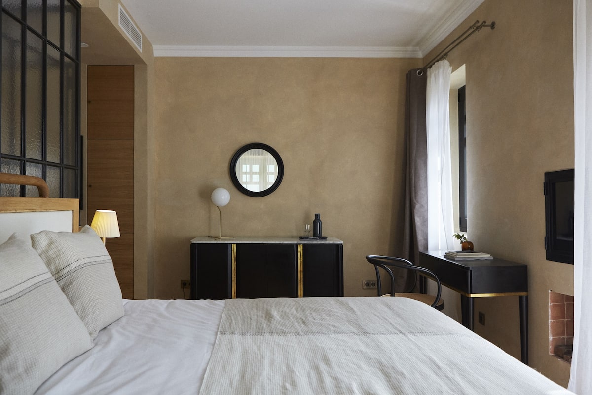 Une chambre d’hôtel avec un grand lit, un bureau avec une lampe, un miroir et une télévision.
