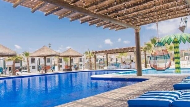 Zona de piscina con sillas de descanso y sombrillas.