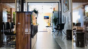 A modern hotel lobby with a central reception desk, seating area, and a large window providing a view of the interior.