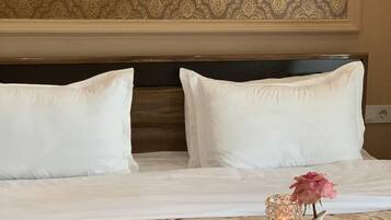 A hotel room with a neatly made bed, a tray with breakfast items, and a vase with a flower.