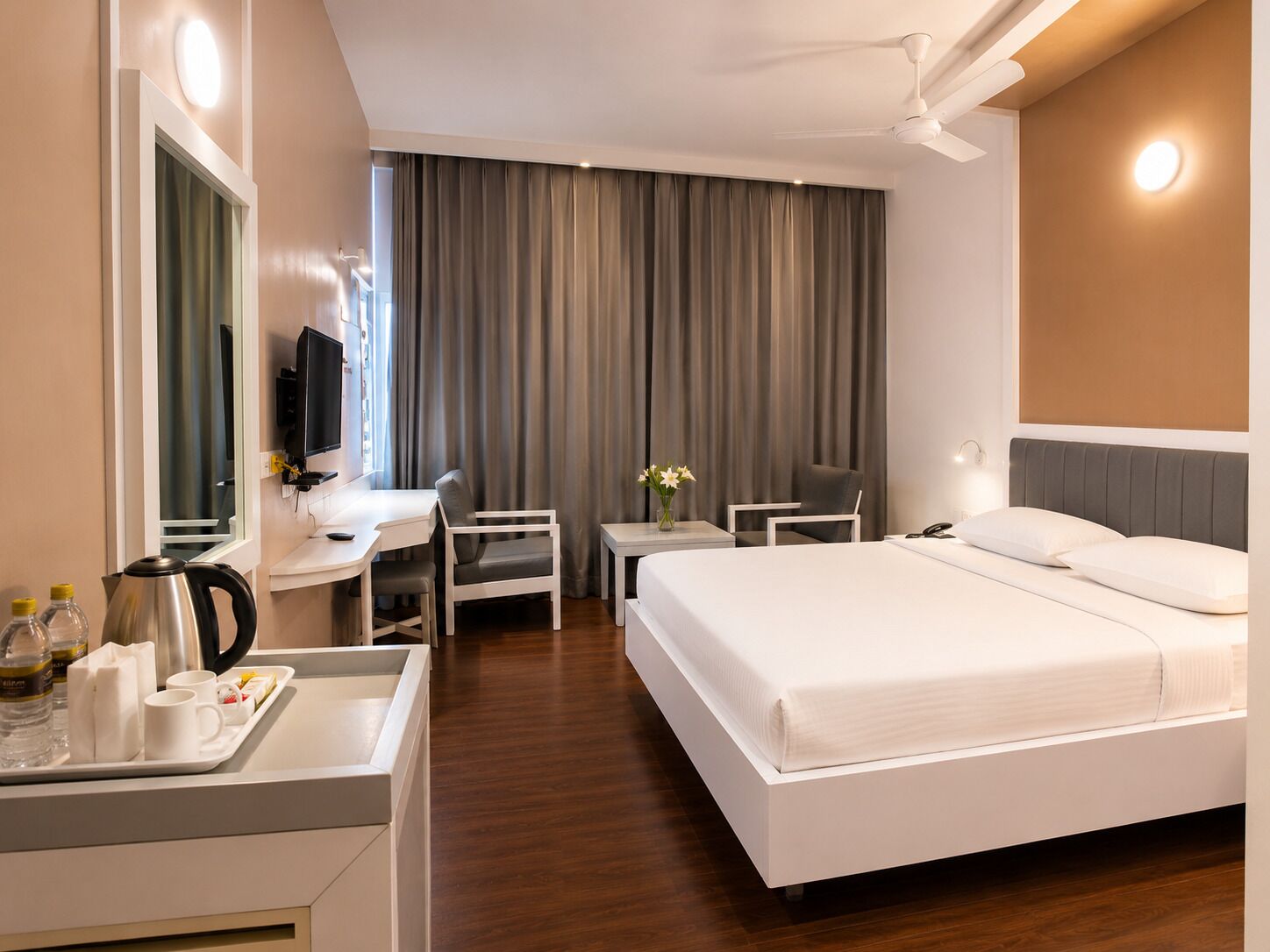 A hotel room with a bed, desk, chair, and a television.