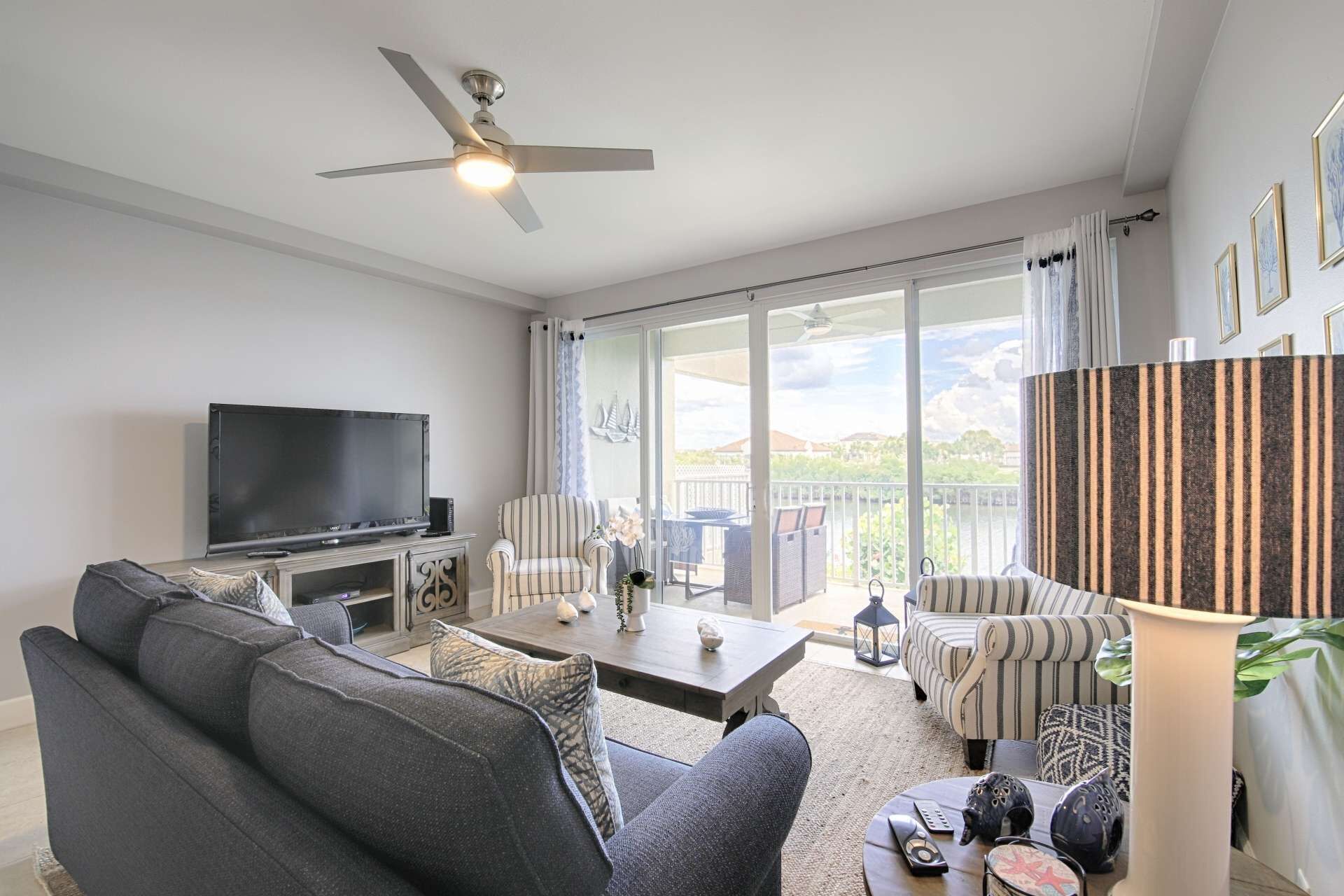 A living room with a TV, sofas, a coffee table, and a balcony with a view.