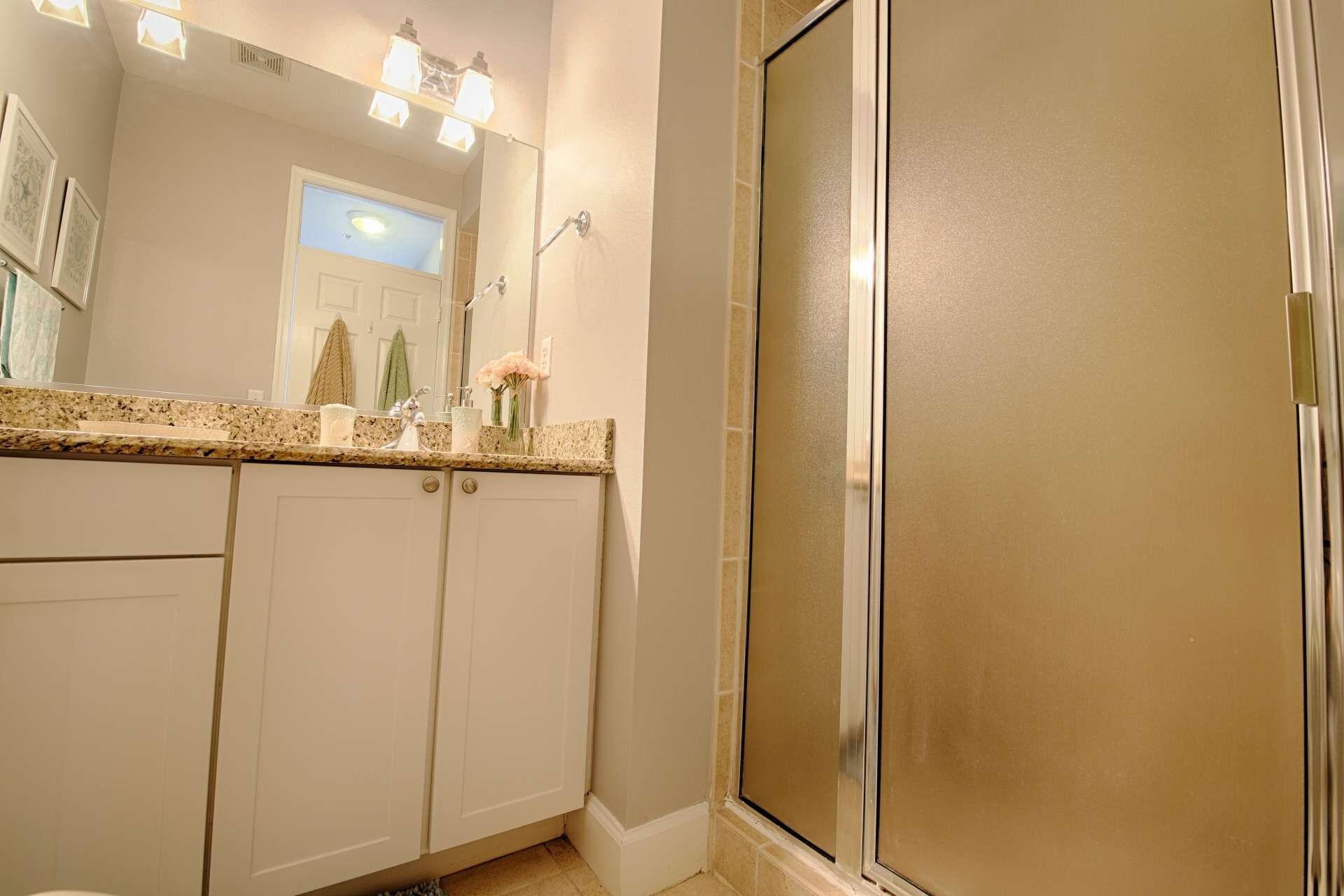 Une salle de bain avec une douche, un lavabo avec un miroir et un porte-serviettes.