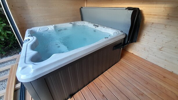 Ein Whirlpool in einer Holzhütte mit einer Holzterrasse und einem Fenster.