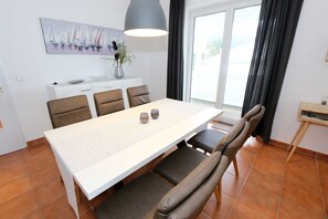 A dining area with a white table, brown chairs, and a vase with flowers. - OS: Haus Holstein Whg. 11 mit Balkon - Haus Holstein Whg. 11 mit Balkon (Sellin)