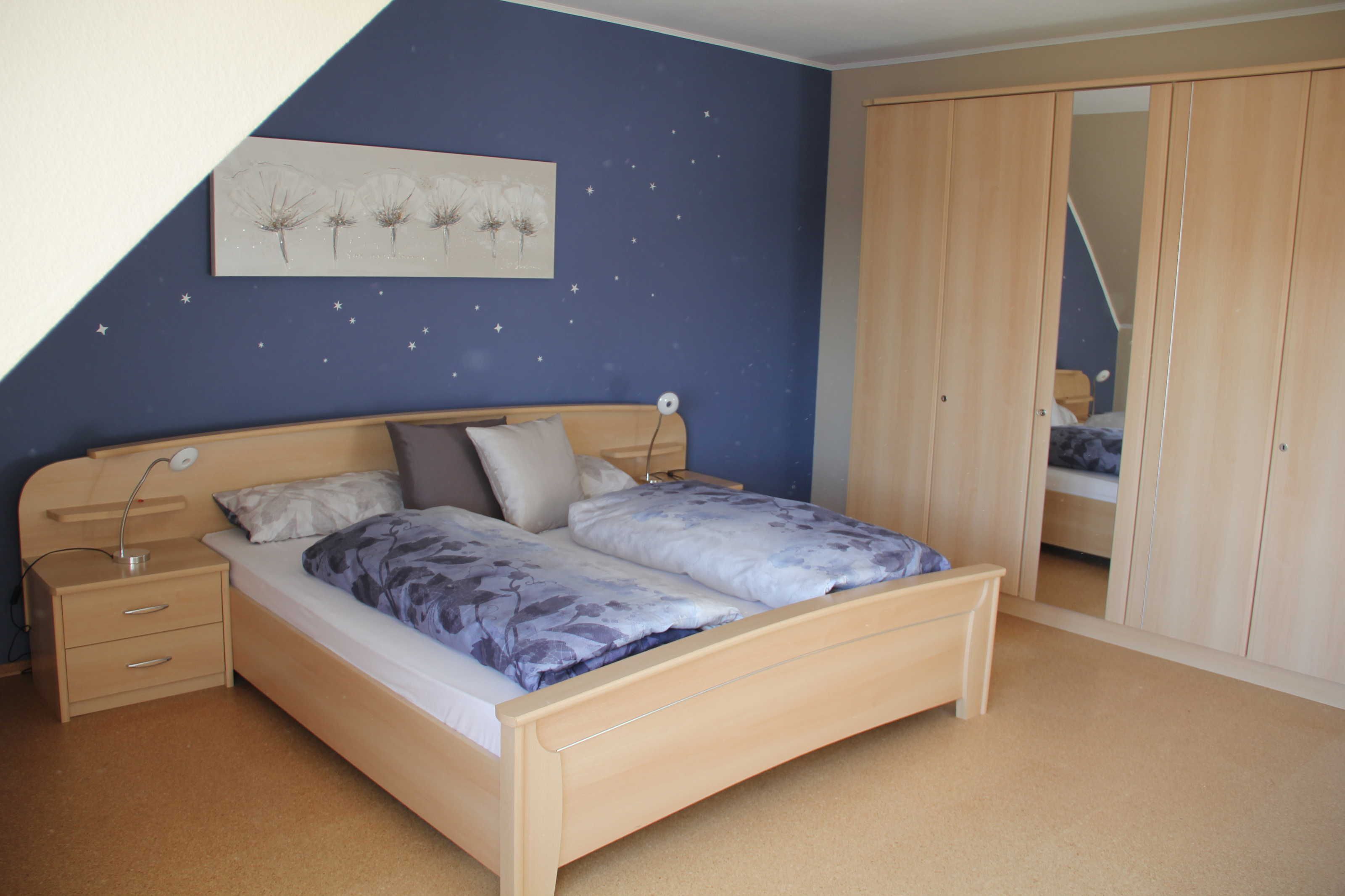 Une chambre à coucher avec un lit, une table de chevet, une lampe et une armoire.