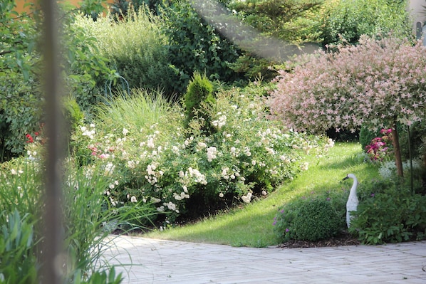 Un jardín con diversas plantas y una estatua de un ave blanca.