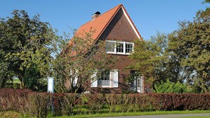 Ein Haus mit rotem Dach, weißen Fenstern und einer Ziegel-Fassade.