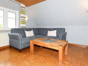 A room with a grey sectional sofa, a wooden coffee table, and a striped curtain.