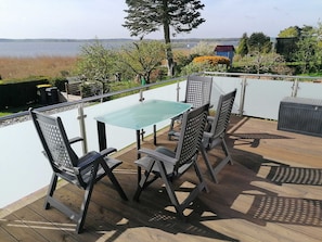 A deck with a glass table and chairs, overlooking a lake. - Ferienhaus Seglerblick am Achterwasser - Ferienhaus Seglerblick (Sauzin)