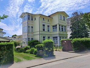 Ein mehrstöckiges Gebäude mit einer hellgrünen Fassade, zahlreichen Fenstern und einem verschlossenen Eingang.