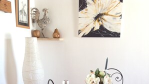 A wooden dining table with a bottle of wine, a bouquet of lavender, and a small bag of cheese on a round wooden board.