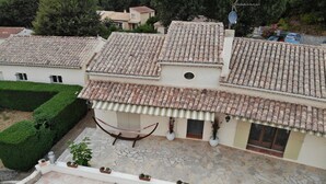 A villa with a tiled roof, a swimming pool, and a hammock.