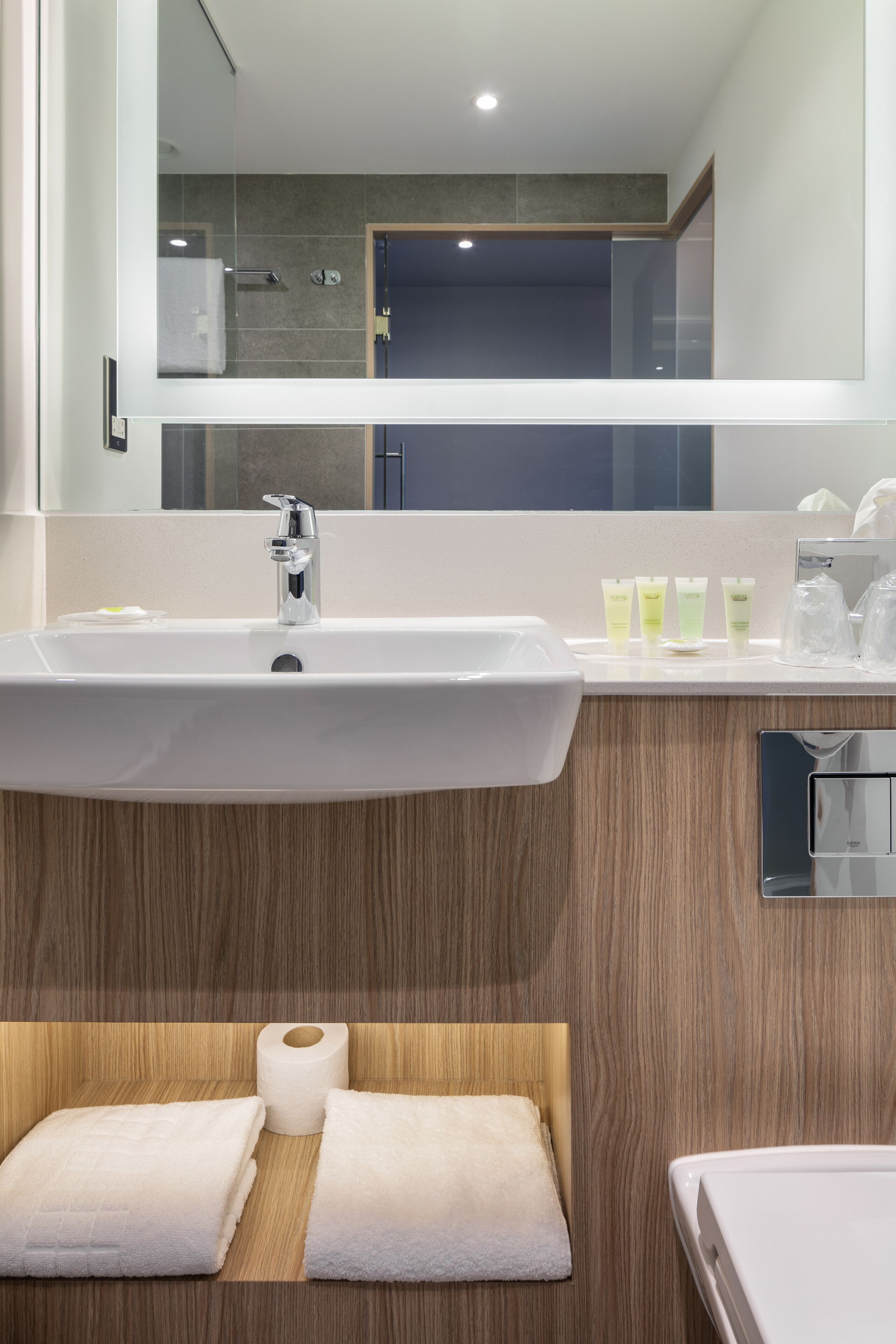 A modern bathroom with a large sink, wooden vanity, and a mirror.