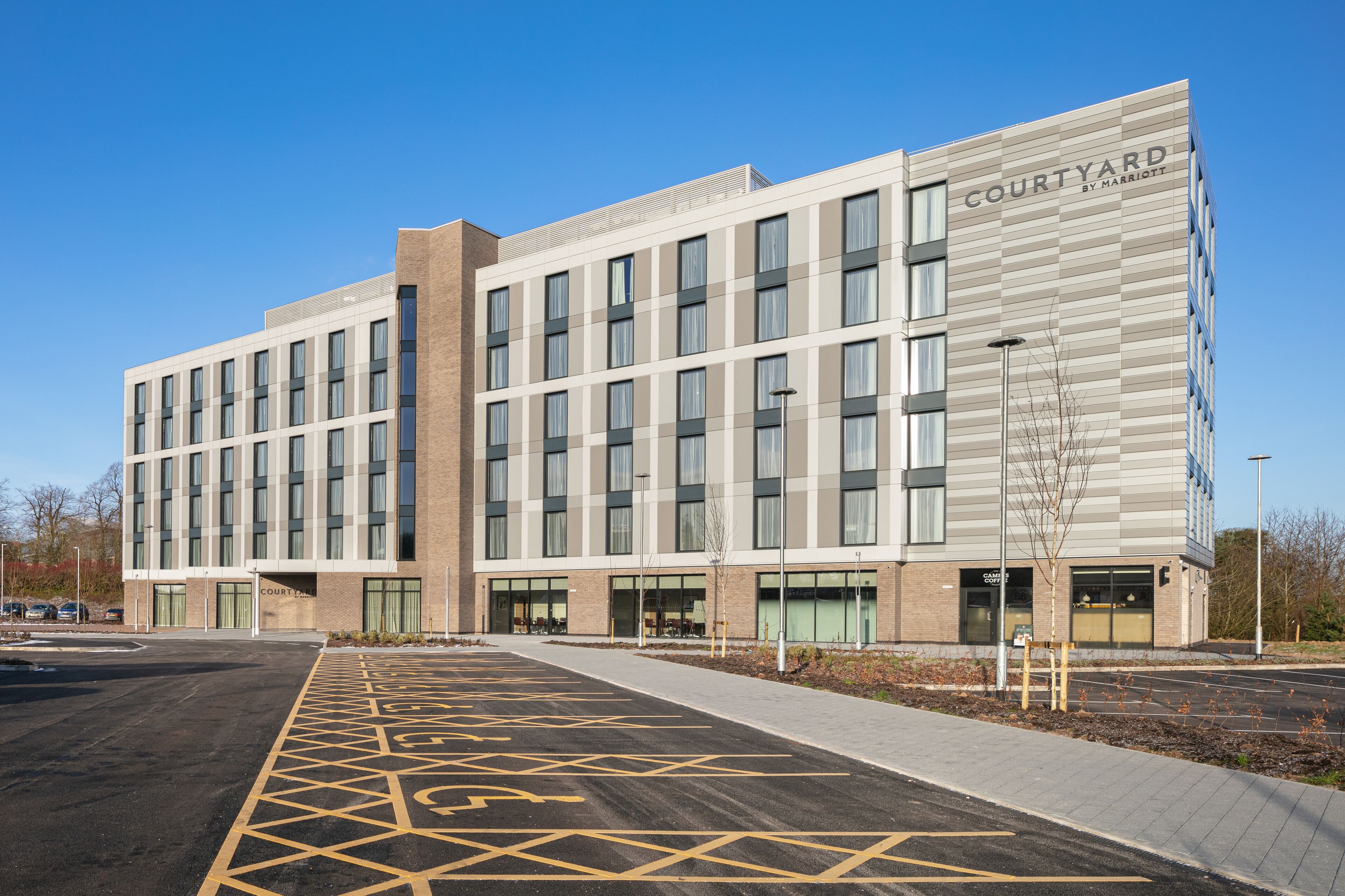 A Courtyard by Marriott hotel with a parking lot and a building facade featuring large windows and a flat roof.