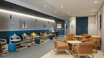 A modern lounge area with seating arrangements, a patterned rug, and artwork on the walls.