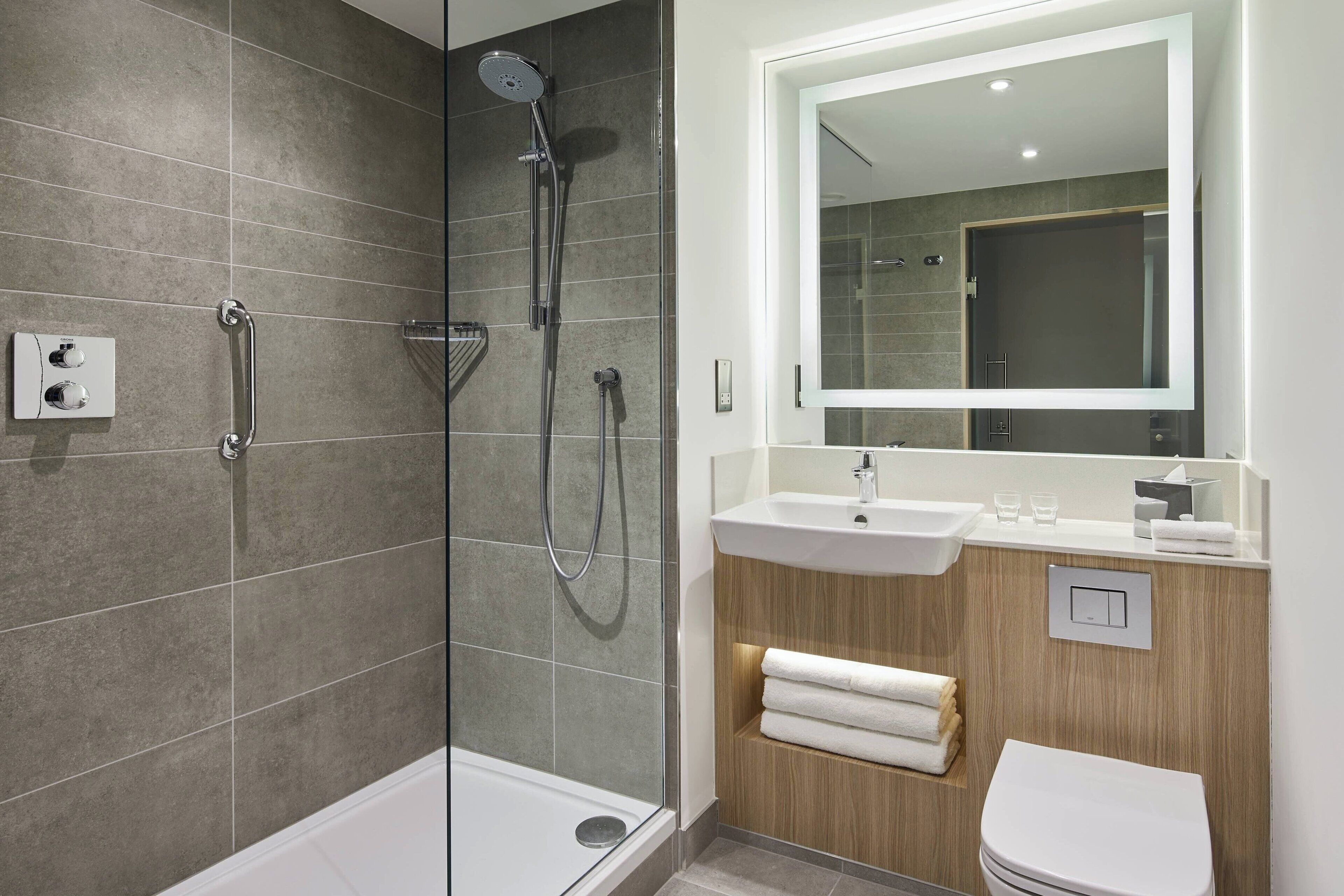 A modern bathroom with a glass-enclosed shower, a wooden vanity with a sink, and a toilet.