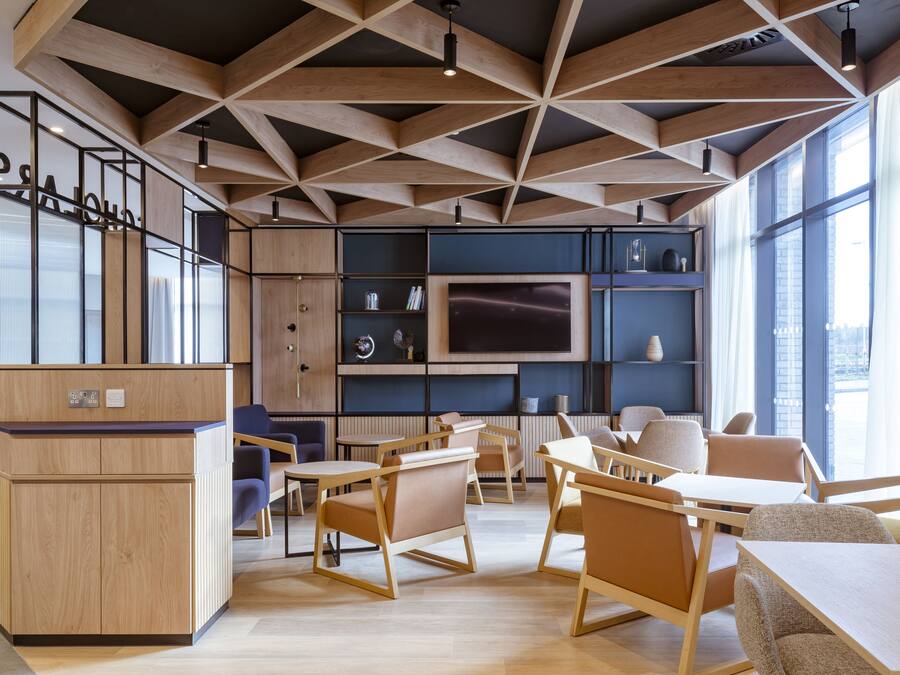 Un espacio de oficina moderno con mobiliario de madera, una recepción y un ventanal que proporciona luz natural.