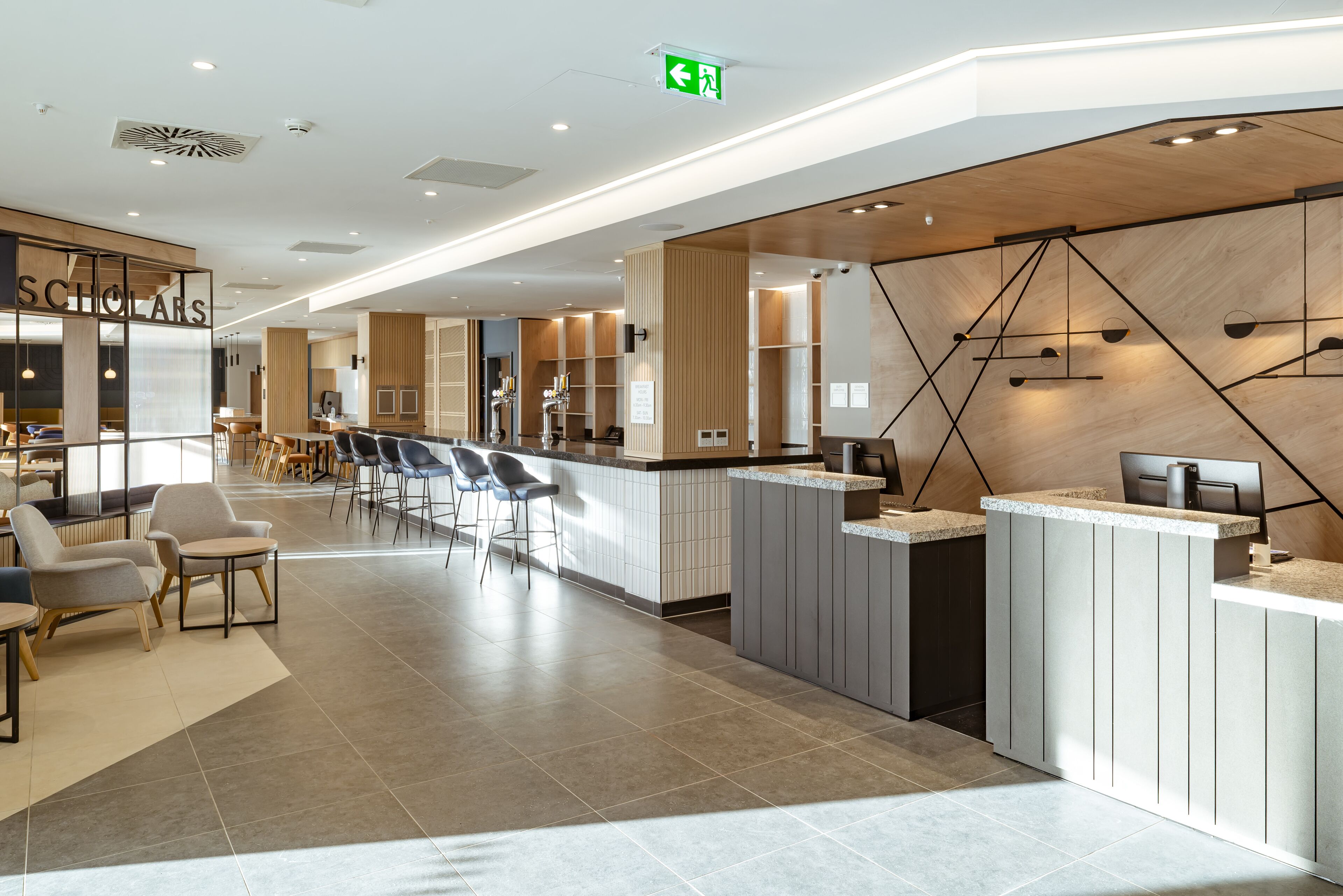 A modern hotel lobby with a reception desk, seating area, and a bar.