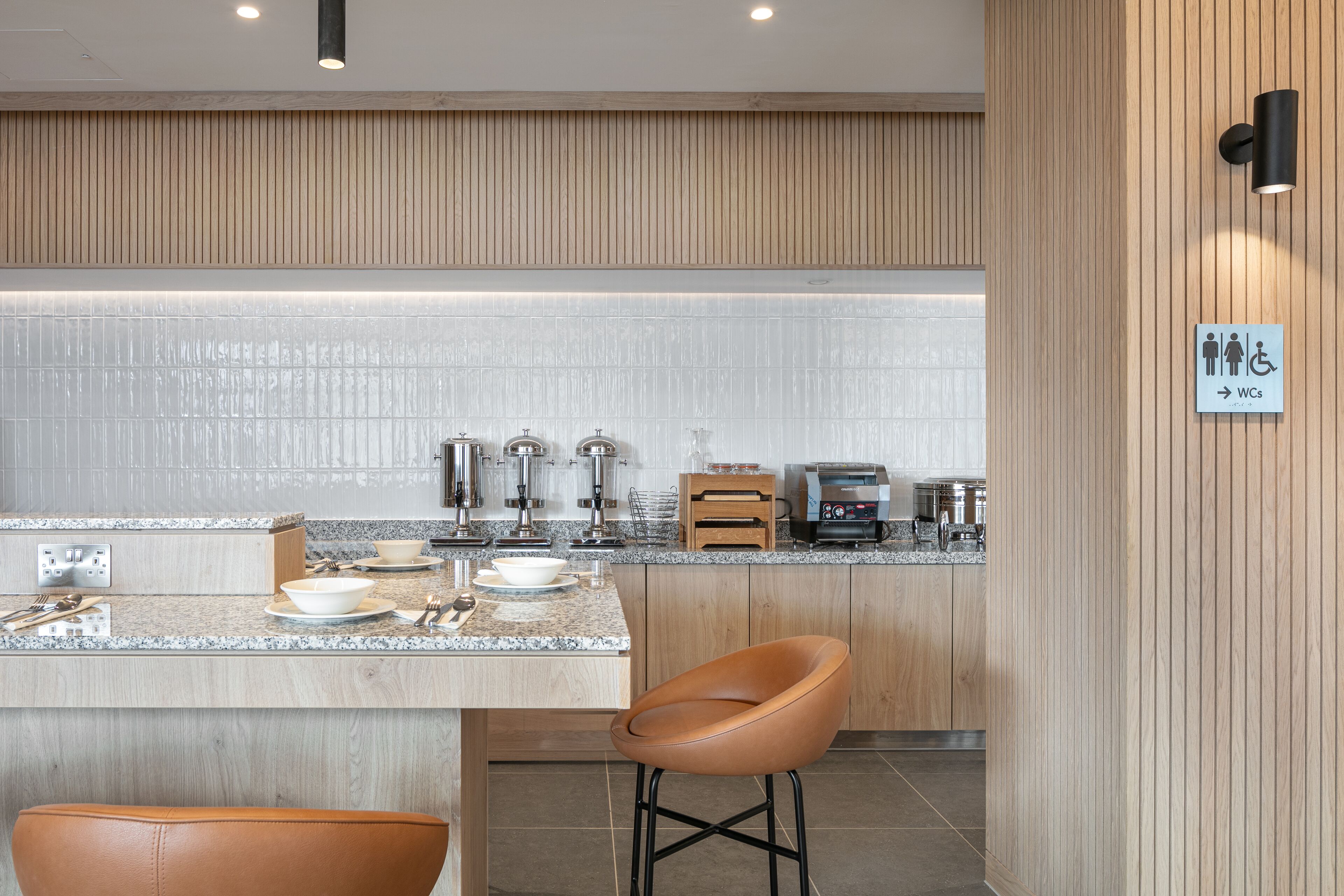 A modern kitchen with granite countertops, stainless steel appliances, and a wooden panel wall.