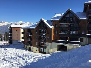 A snow-covered building with multiple balconies and a ski slope in the background. - 4-room duplex for 8 people at the foot of the slopes in Morillon (Morillon 1100)